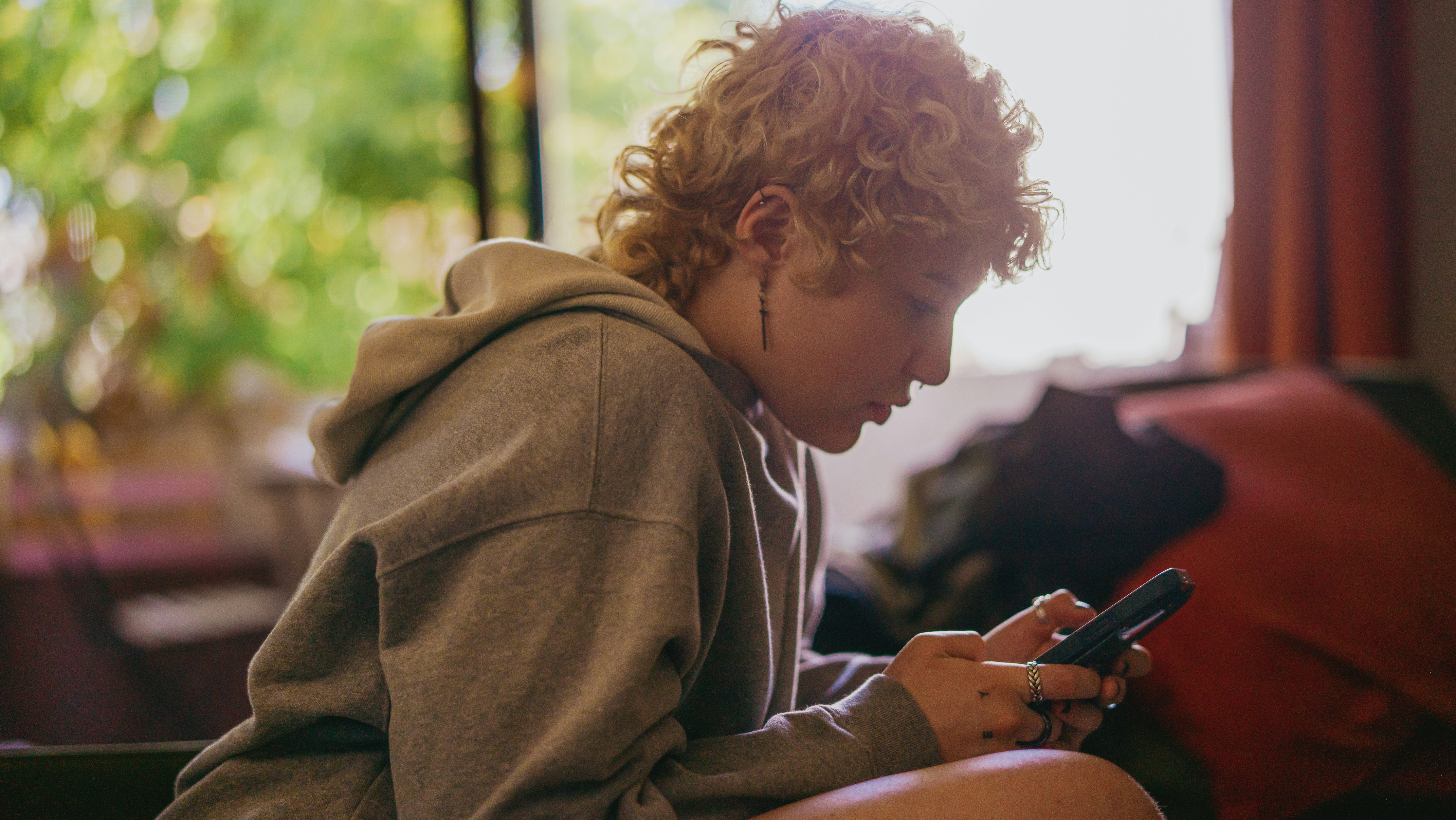 Porträtt av en icke-binär autistisk person som använder sin mobiltelefon inomhus